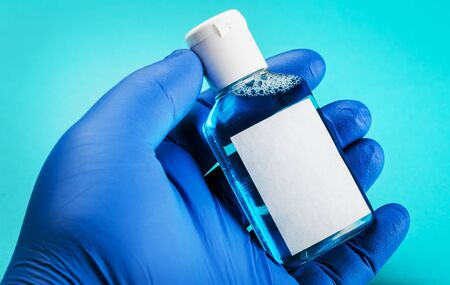 hand in rubber gloves holds personal protective equipment against the coronavirus antiseptic liquidの写真素材