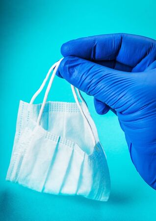 hand in rubber gloves holds personal protective equipment against coronavirus infectionの写真素材