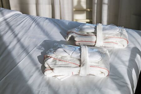 set of Bathrobe and Slippers are on the bed in the hotel roomの写真素材