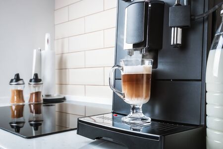 glass cup with hot cappuccino prepared in the coffee machineの写真素材