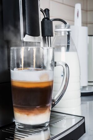 glass cup with hot cappuccino prepared in the coffee machineの写真素材