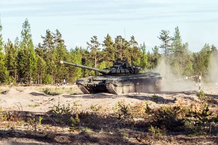 battle tank rides on a dusty road in the forest. Advanced tank of the Russian army t-90