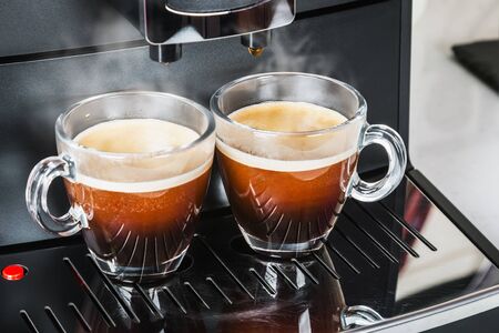 glass cups with hot coffee poured from the coffee machineの写真素材