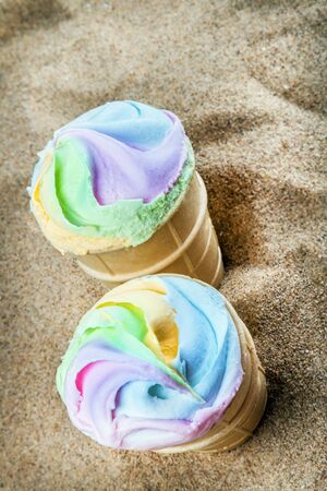 creme brulee ice cream with bright rainbow colors in a waffle Cup on the sand on the beach. Cooling down in the heat on the beachの写真素材