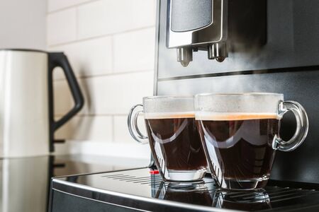 glass cups with hot coffee poured from the coffee machineの写真素材