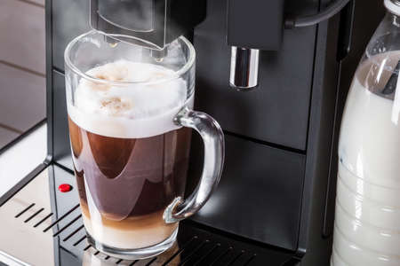 glass cup with hot cappuccino prepared in the coffee machineの写真素材