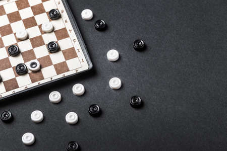 game of checkers played on a back background. Magnetic road checkers gameの写真素材