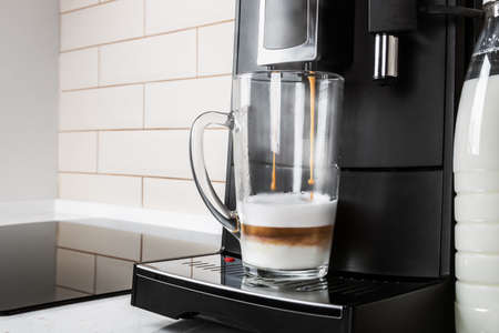 glass glass of cappuccino is prepared in the coffee machine at homeの写真素材