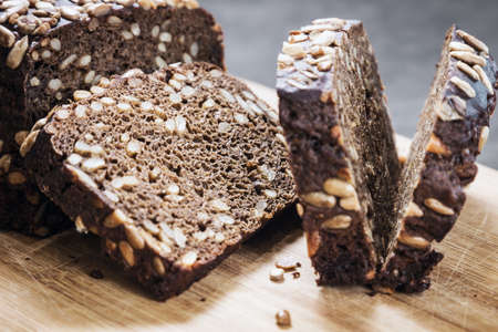 black whole grain bread with seeds and cereals cut into piecesの写真素材