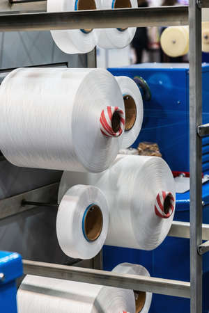 bobbins with white threads on the shelves of a clothing factory