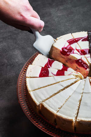 hand with the dessert spatula takes a piece of cheesecakeの写真素材
