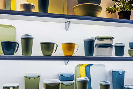 different colors of plastic tableware, boxes, plates and glasses are on the counterの写真素材