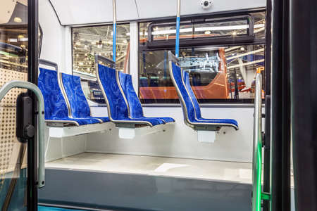 modern and comfortable city bus, an electric bus or cabin with suspended empty passenger seatsの写真素材
