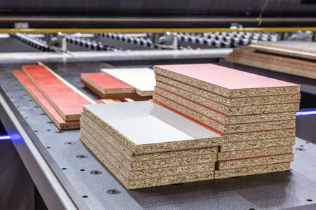 particle boards are stacked on a wood-cutting machineの写真素材