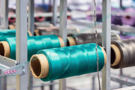 bobbins with threads of different colors on the machine of a clothing factory