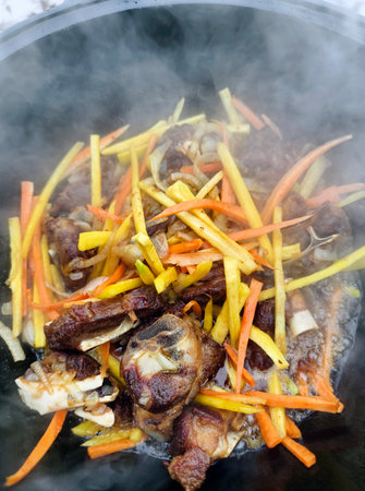 cooking lamb pilaf in a cauldron over a fireの写真素材