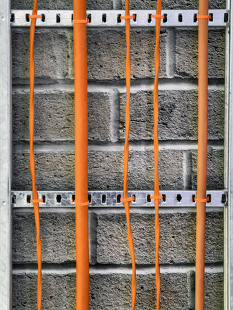 Orange cables run along a gray brick wall, showcasing a modern industrial aesthetic in a...