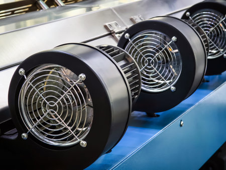 Industrial cooling fans arranged in a row on machinery in a factory setting during daytime operationの写真素材