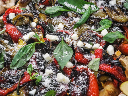 Colorful vegetable pizza topped with herbs and cheese served on a wooden board in a warm settingの写真素材