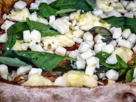Savoring the fresh flavors of a homemade pizza topped with basil, mozzarella, and a drizzle of olive oil at a local kitchenの写真素材