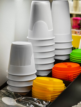 Stacked colorful cups and lids arranged neatly on display in a kitchen or cafe environmentの写真素材