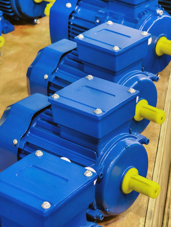 Blue electric motors arranged in a row on a wooden surface in a workshop setting, showcasing their design and constructionの写真素材