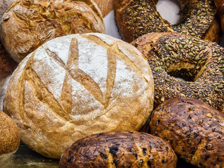 Artisan bread display featuring various types of loaves and rolls at a bakery in the morning sunlightの写真素材