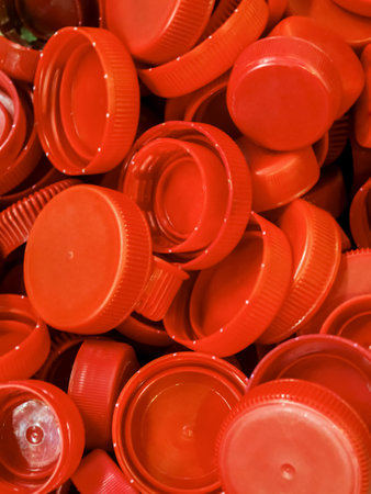 Bright red bottle caps collected in a pile showcasing recycling potential at a local facilityの写真素材