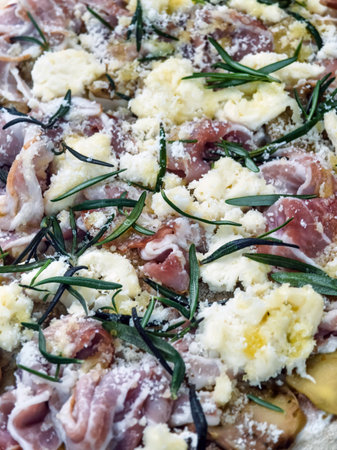 Delicious homemade pizza topped with fresh herbs, cheese, and savory meat prepared in a cozy kitchen settingの写真素材