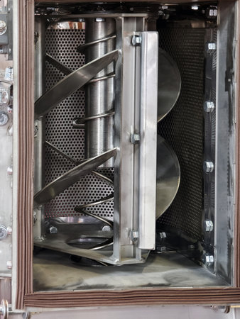 Industrial mixing machine shows rotating blades and stainless steel interior in factory environmentの写真素材