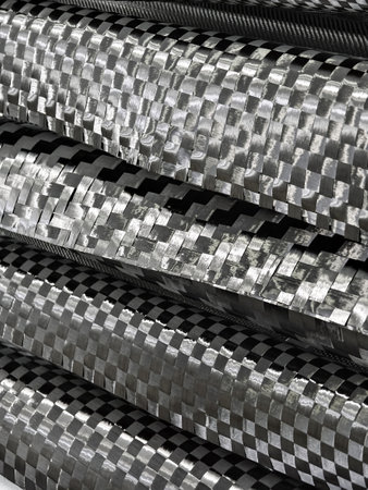 Textured carbon fiber materials stacked in layers showcasing intricate woven patterns and shine under studio lightingの写真素材