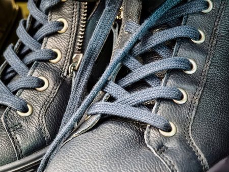 Detailed close-up view of navy blue laced shoes showcasing craftsmanship and design in a modern urban settingの写真素材