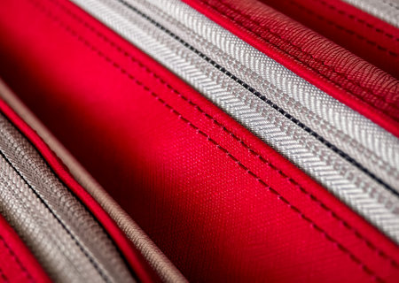 Detailed close-up view of textured patterns on fabric in shades of red and gray used for a travel accessory or luggage itemの写真素材