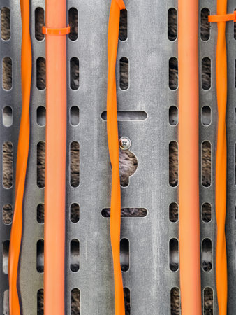 Innovative construction material features orange tubes and metal strips laid out in a creative design with textureの写真素材