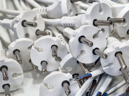 Collection of white electrical plugs piled together on a flat surface in a workshop settingの写真素材