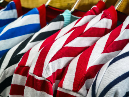 Various striped shirts in bold colors hang neatly on display at a trendy clothing store. The vibrant patterns attract attention and highlight modern fashion trends.