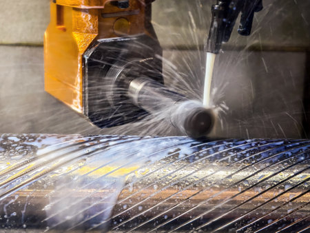 Metal cutting process in a workshop with water coolant spraying on a rotating shaftの写真素材