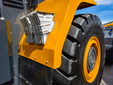 Heavy machinery tire and fender details capture in bright sunlight at construction site during daytime activityの写真素材
