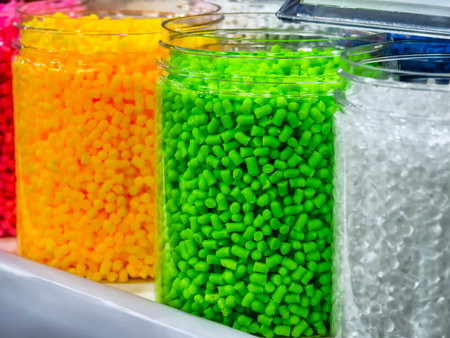Bright colorful plastic pellets displayed in storage jarsの写真素材