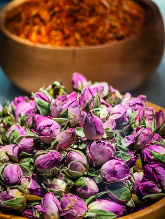 Dried purple rosebuds and saffron displayed in traditional wooden bowls at a local market in the afternoon lightの写真素材