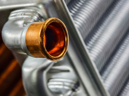 Close-up view of a metallic automotive part showcasing intricate details and vibrant copper finish in a workshop settingの写真素材