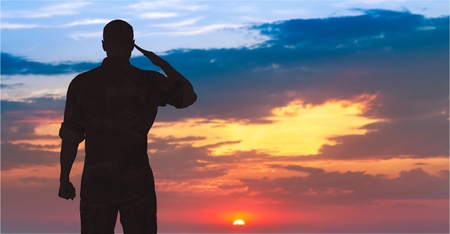 Silhouette of a soldier saluting during sunset.の写真素材