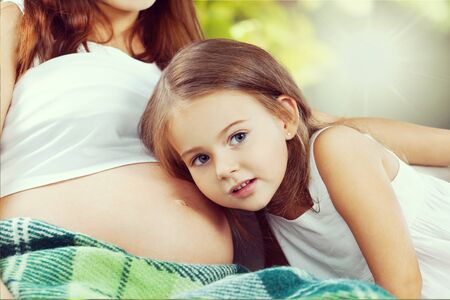 Child listens to a pregnant woman.の写真素材