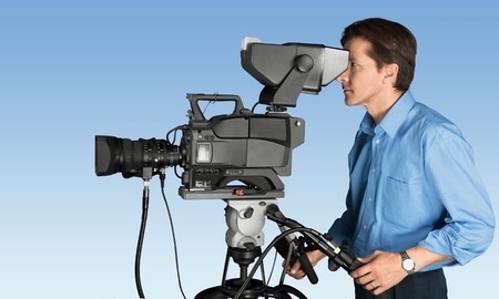 Presenter talking to camera in a green screen studio with silhouetted cameraman in foreground and...