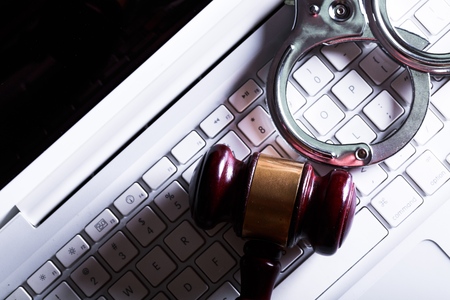 handcuffs and judge gavel on computer cyber crime conceptの写真素材