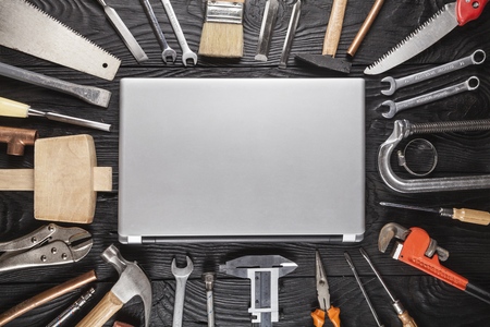 Laptop on a work table with DIY and construction tools all around, top view, hobby and crafts...