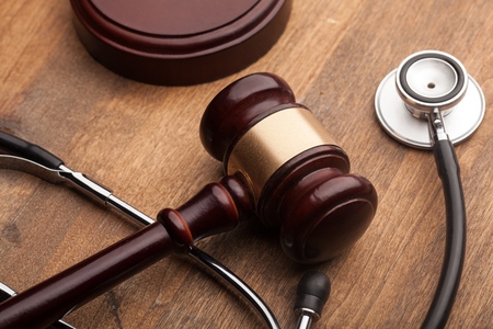 Gavel and stethoscope on a wooden surface.の写真素材
