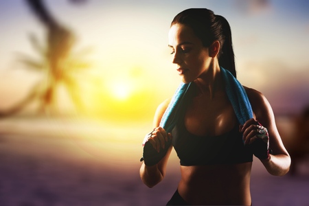 Back view of strong motivated woman celebrating workout goals towards the sun. Morning healthy training success.の写真素材