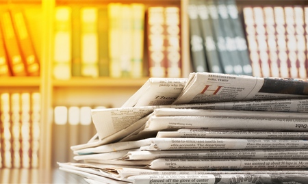 Newspapers folded and stacked on the table with garden. Closeup newspaper and selective focus image. Time to read concept.の写真素材