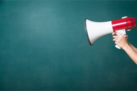 hand with a megaphone in front of an empty blackboard